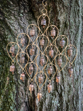 A gold-colored wind chime with 23 metal bells of varying sizes, each hanging from a small chain.